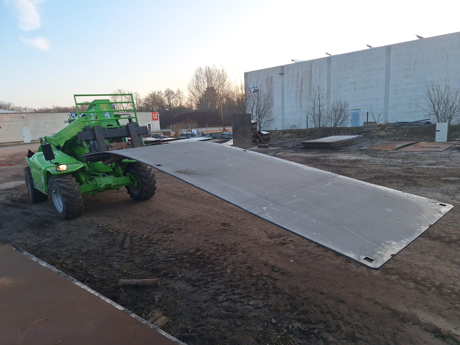 Gabelstapler transportiert großformatige Stahlplatten auf Industriegelände